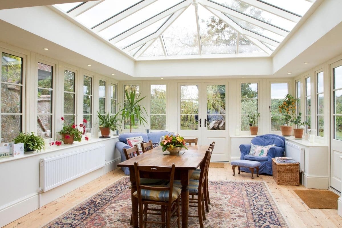 Inside a large bright traditional timber orangery dinning and living area extension