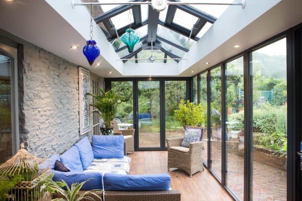 Inside a modern aluminium orangery with slate grey finish and finials and a stylish lantern roof