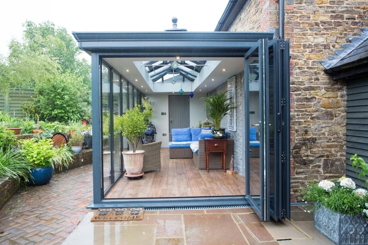 Aluminium slate grey orangery extension with bi-fold doors open wide out onto the small patio