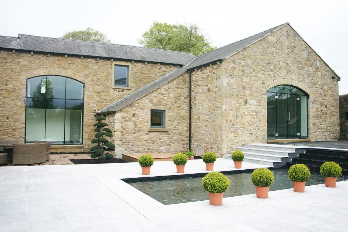 Frameless glass windows and doors create a stunning aesthetic in this stone country property