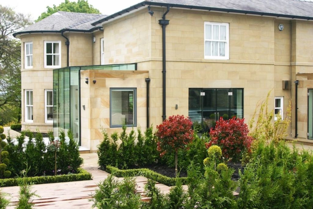 A small glass box extension and frameless glass windows create a modern and stunning aesthetic