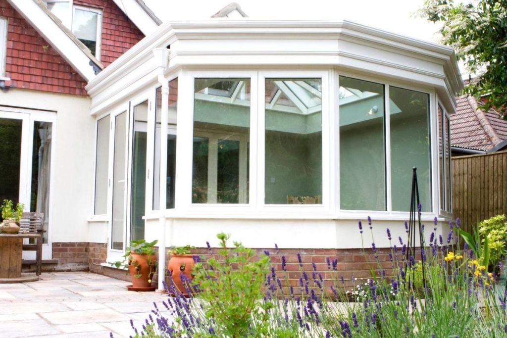 Elegant white timber framed hexagonal orangery with dwarf brick walls