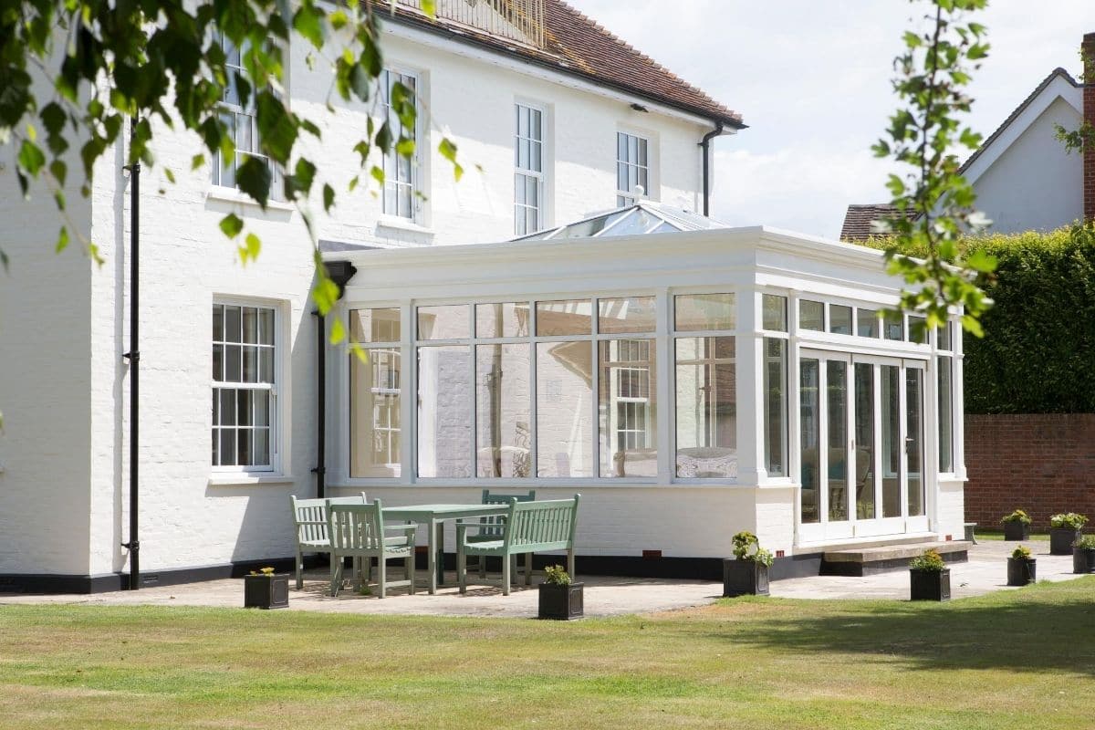 Side aspect of large white timber conservatory with dwarf painted brick walls