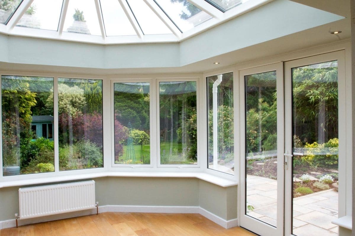 Inside a white timber hexagonal orangery with dwarf walls painted with a subtle olive green shade