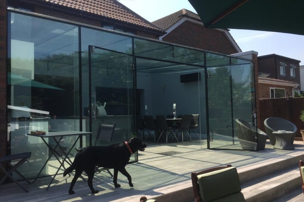 frameless glass double doors open up this glass box kitchen extension to a sunny decking area