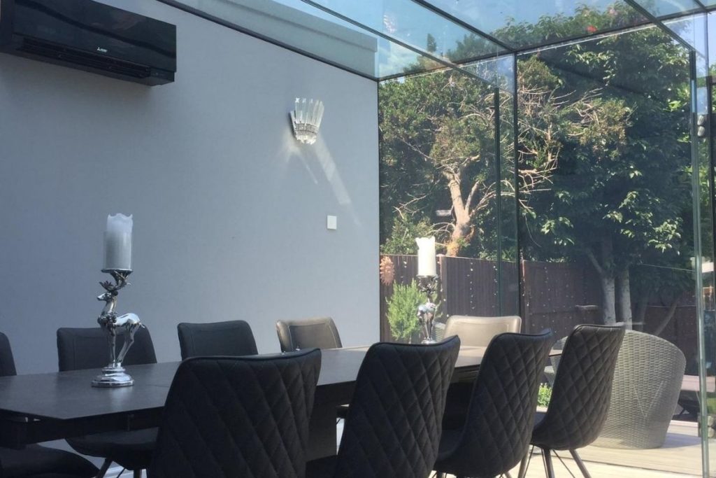 A beautiful glass dinning room extension with a full frameless glass roof flooded with sunlight