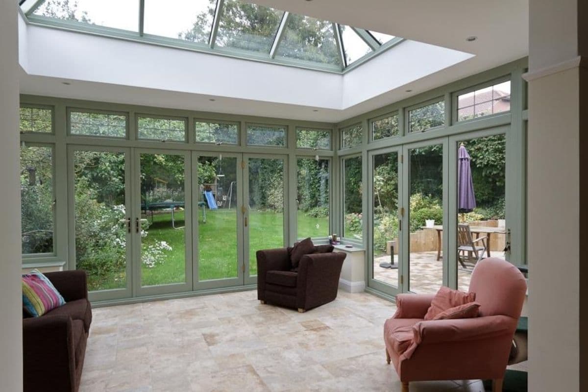 Inside a spacious orangery with sage green painted finish frames
