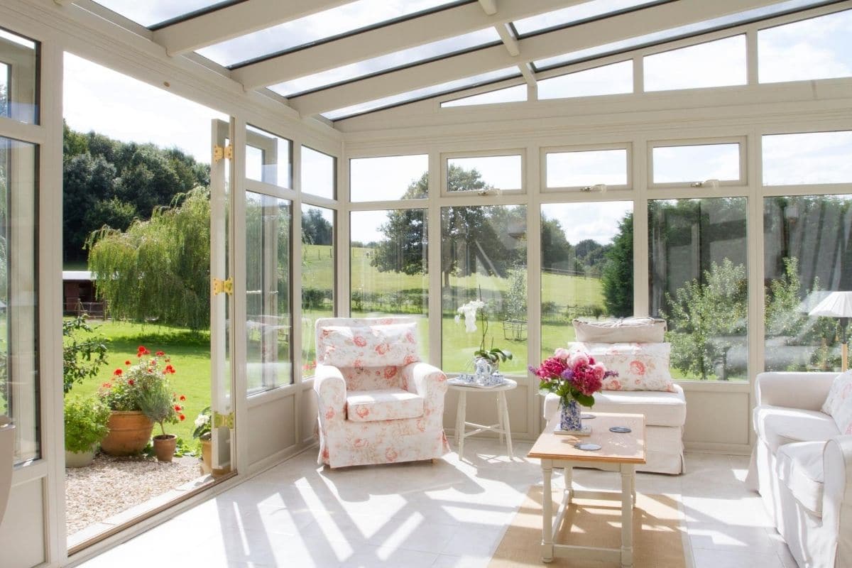Inside of white timber framed lean-to conservatory with double doors out to the garden