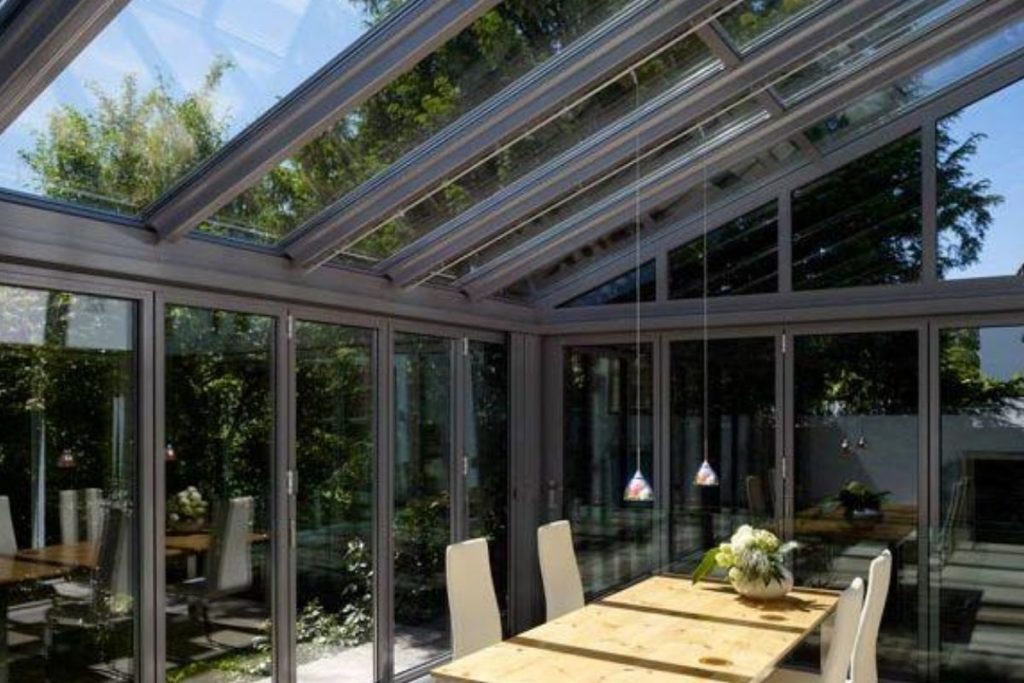 Large lean-to conservatory dinning space with modern deep grey aluminium frames and bi-fold doors