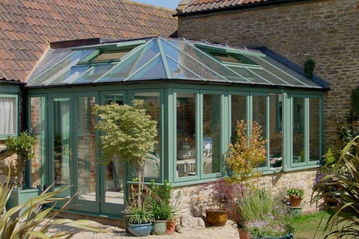 Green aluminium conservatory with traditional stone dwarf walls and roof light windows