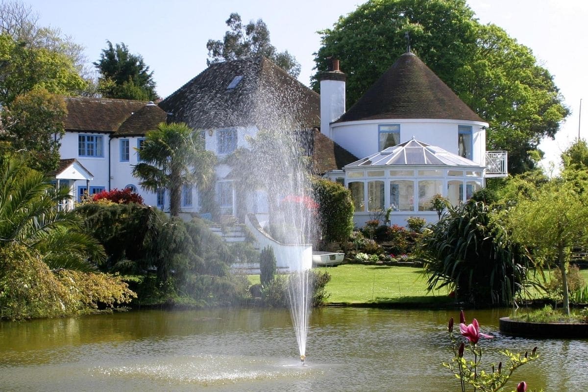 Large round white timber framed conservatory in beautiful gardens with a view of the lake