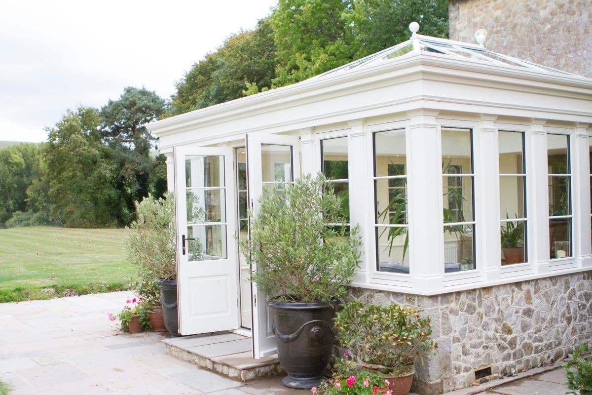 White timber orangery extension with stone dwarf walls to match the aesthetic of the lister property