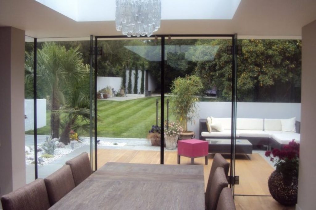 Modern dining room with a focal lantern roof and frameless glass rear wall and double doors