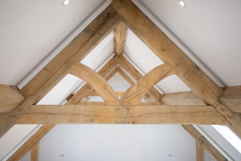 Wooden beams forming a triangular structure in a bright, modern interior, showcasing craftsmanship ideal for bespoke glass extensions and enhancing residential aesthetics.