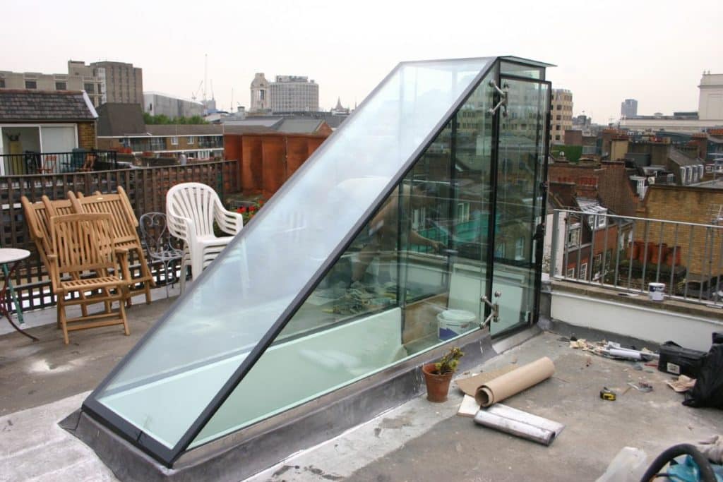 A contemporary space saving frameless glass rooftop stairway cover