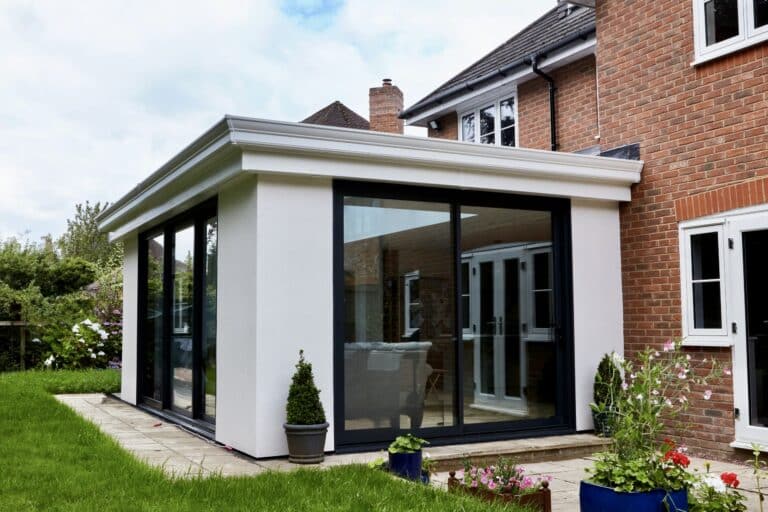 Contemporary flat-roof glass extension with large sliding doors opening to a landscaped garden
