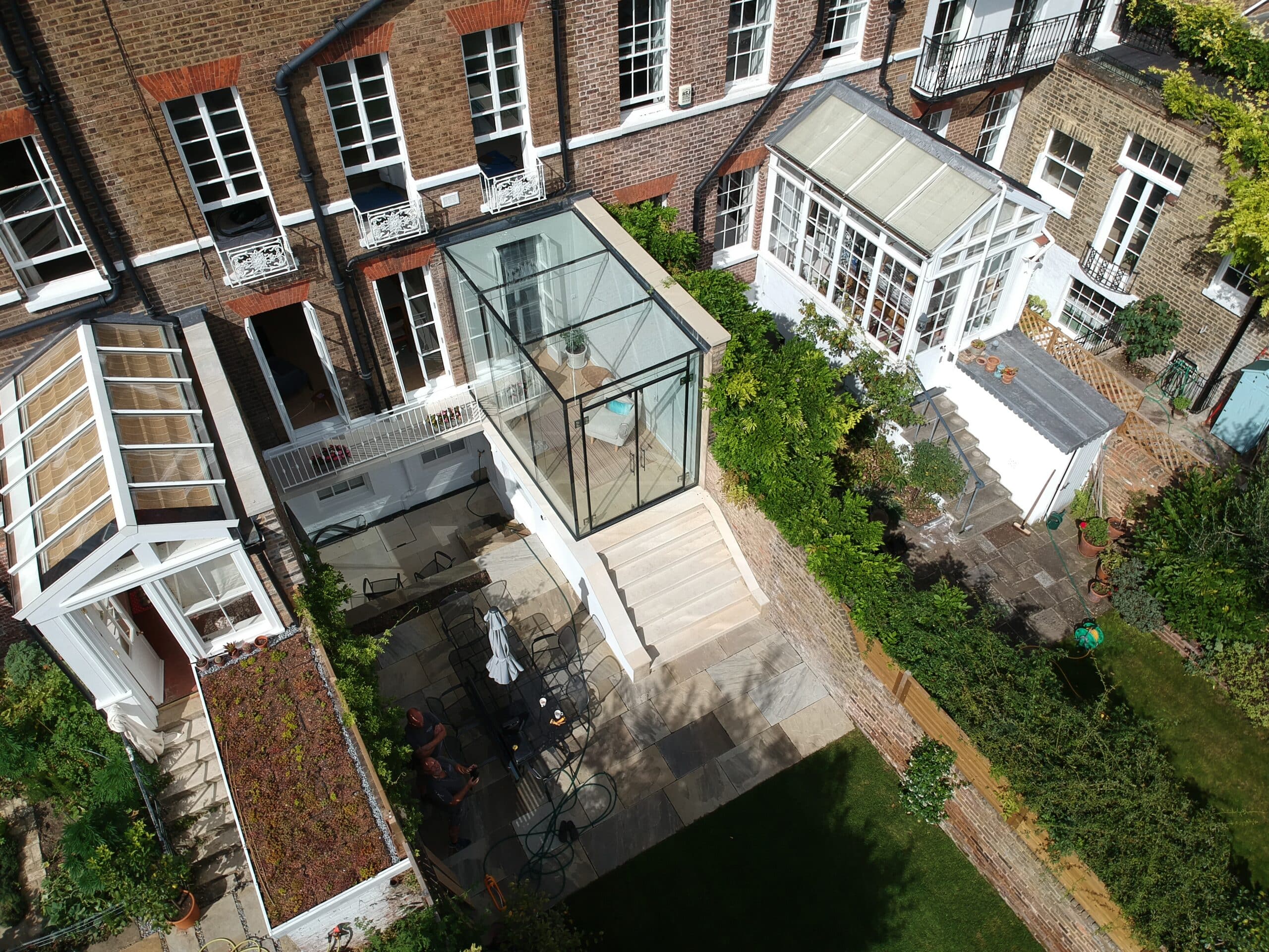 Drone view of frameless glass box on a terraced townhouse
